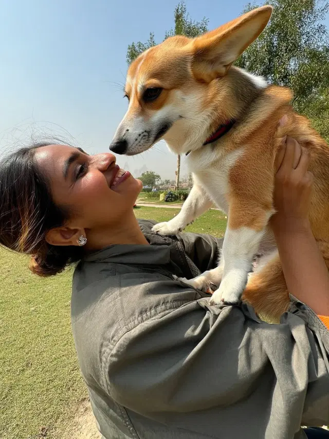 Priya holding her Corgi outdoors on a sunny day